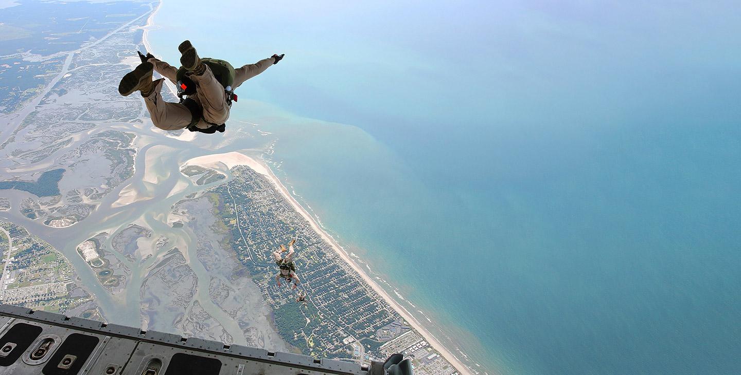 携带降落伞的作战人员从配备了飞机技术的C-17飞机的后部跳下 