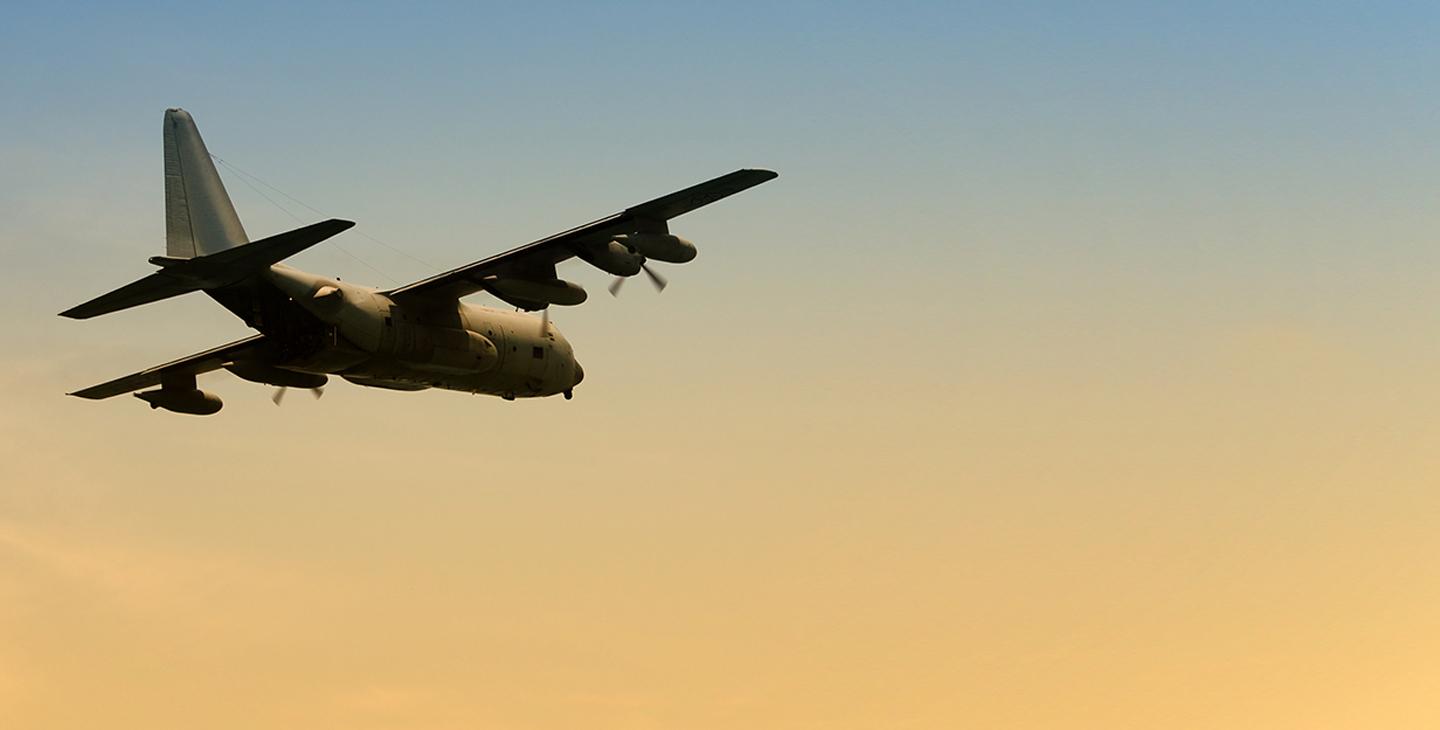 C-130 aircraft flying at dawn