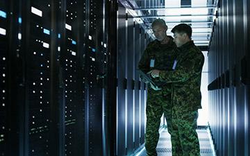 Two men dressed in army greens standing in a server room