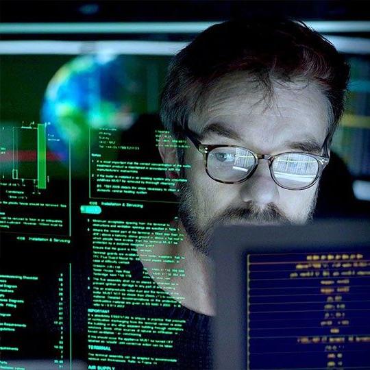 Man looking at a string of code on a computer screen