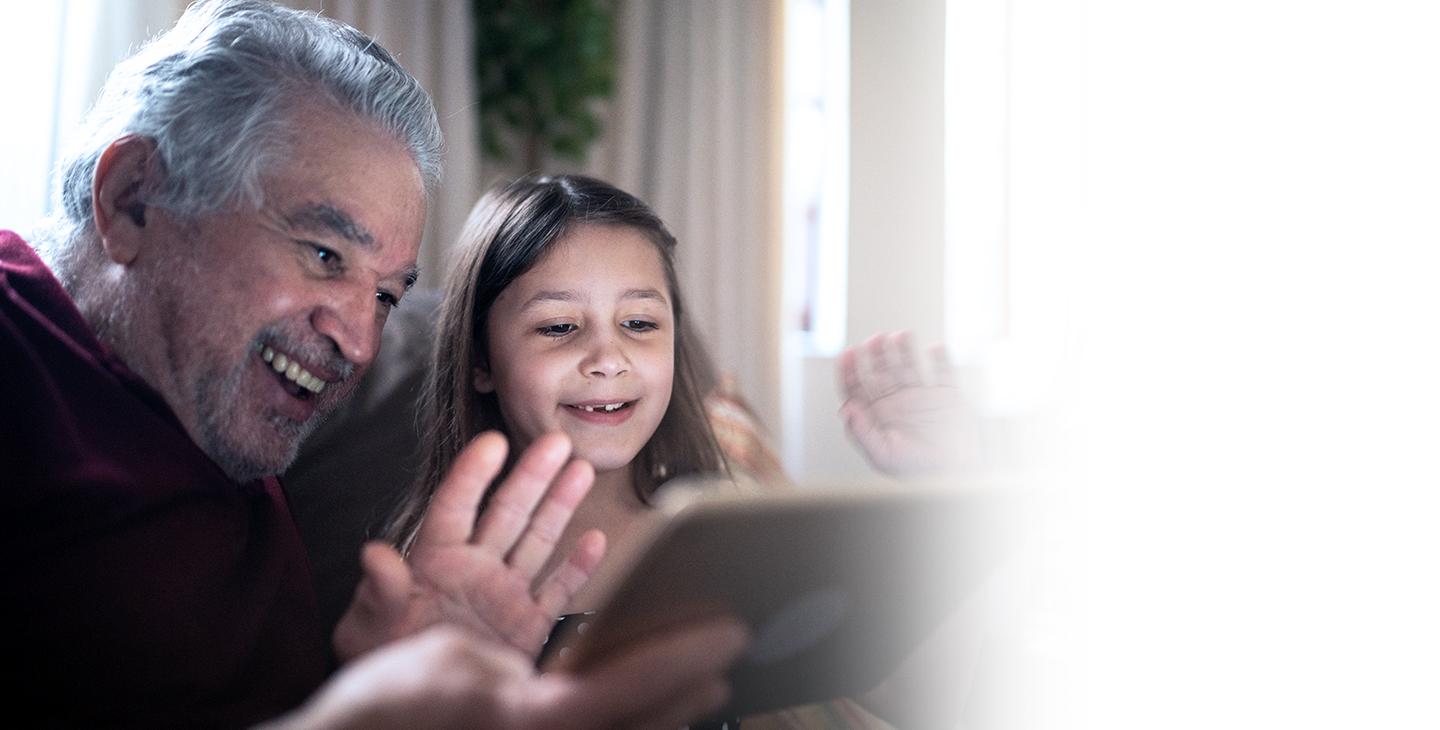 孩子和祖父坐在一起，在联邦通信委员会的平价连接计划的帮助下，用平板电脑上网.
